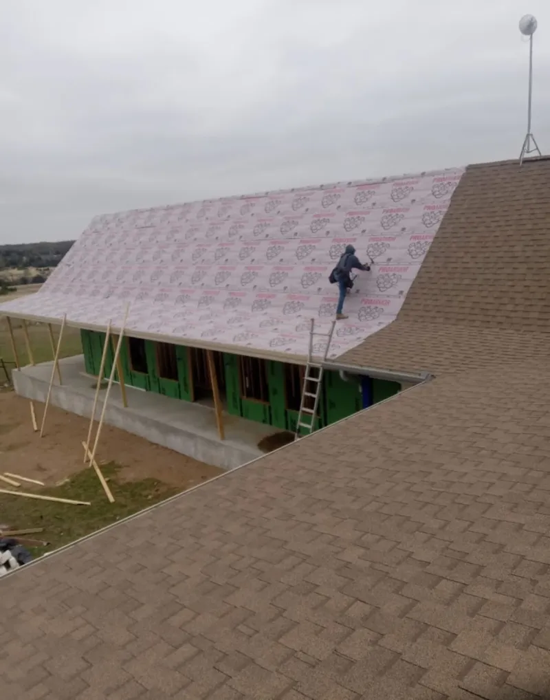 Worker preparing underlayment for a metal roof installation in Oakland